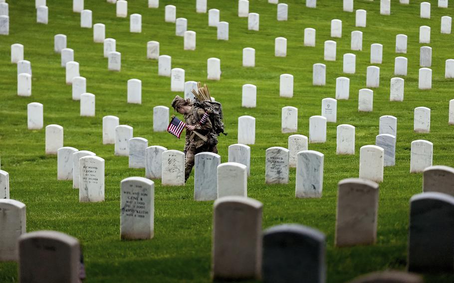 An American soldier places flags at the headstones of her fellow past service members.