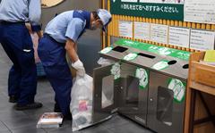 A worker empties a trash receptacle at Azabujuban Station in central Tokyo, Wednesday, April 27, 2022. 
