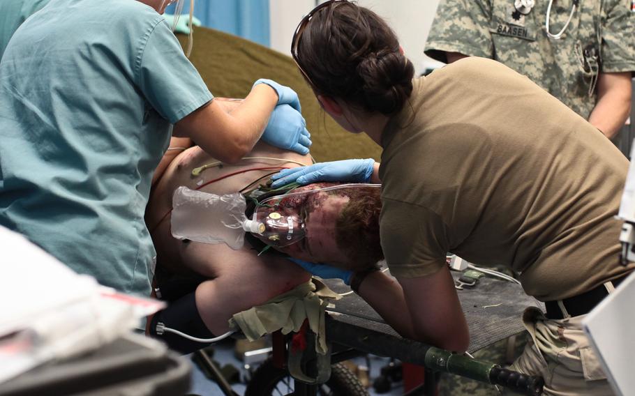 A soldier is rolled over onto his side by medical professionals