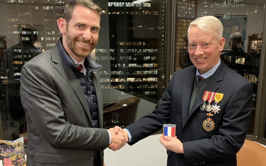 Charles Hugonnet of the French Embassy in Canada presents Guy Black, right, with a French military emblem to wear this spring in South Korea during a 187-mile walk to commemorate a Korean War battle. 