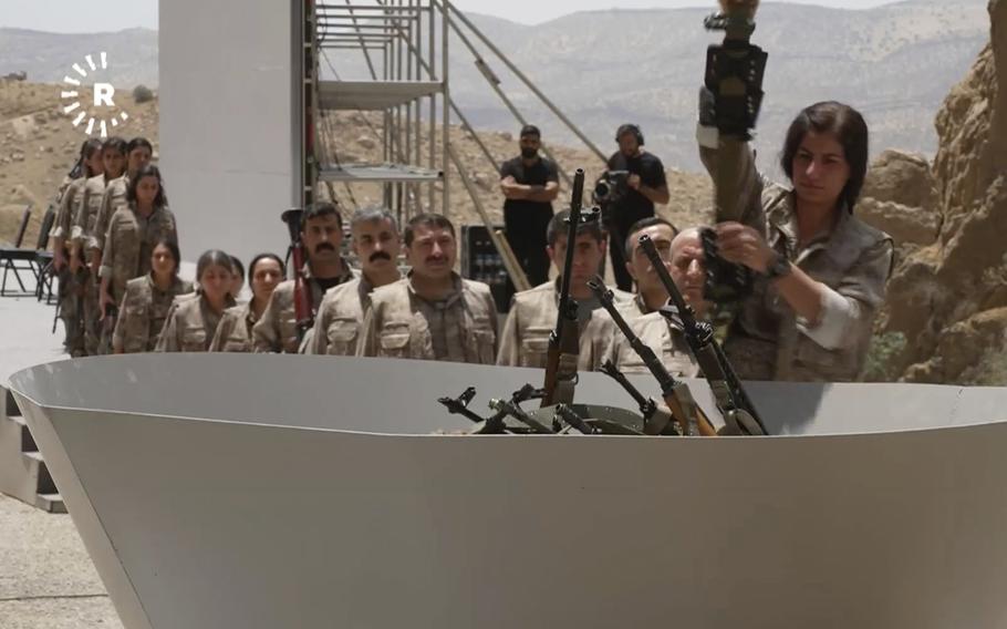 Kurdish militant fighters place their guns in a cauldron to be set on fire.