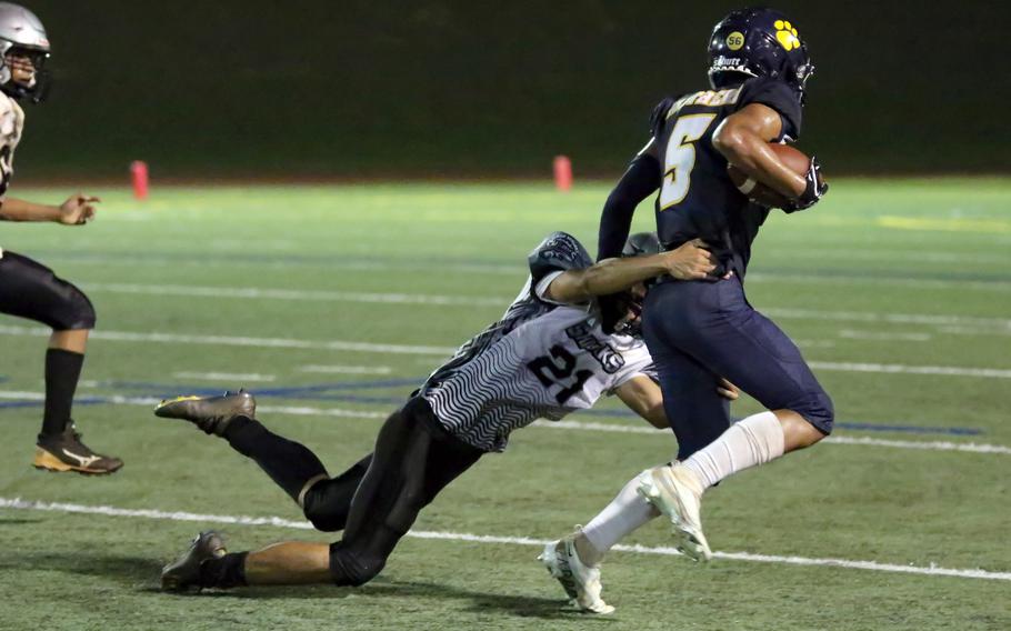 Guam High's Joey Delia evades a pair of Simon Sanchez tacklers.