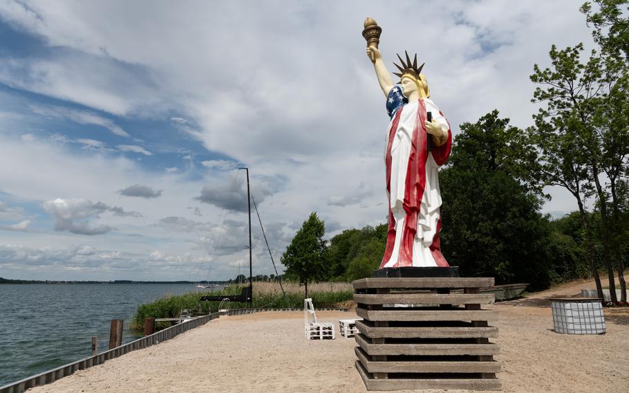 A Statue of Liberty replica overlooks a lake.