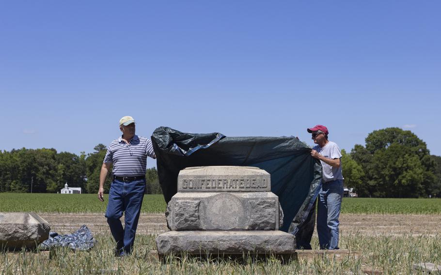 Volpe Boykin, 63, left and his friend David Jones, 64, uncover a portion of the Confederate monument moved from in front of the Isle of Wight County Courthouse and relocated to a farm Boykin owns. 