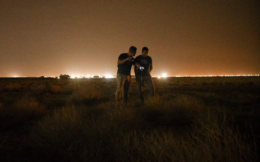 Army Spc. Joseph Neitz points out possible hiding spots for scorpions with Staff Sgt. Eric Bejarano while walking through the desert near Ali Al Salem Air Base in Kuwait on Nov. 28, 2022. 