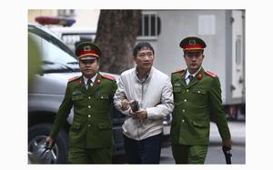 Trinh Xuan Thanh, center, is led into a courtroom by police in Hanoi, Vietnam, Wednesday, Jan. 24, 2018. Thanh, former chairman of state energy giant PetroVietnam's construction arm, is accused of embezzling $622,000 from a property project. Thanh was sentenced to life in prison on Monday for embezzlement in thermo power plant. Germany in August accused Vietnamese agents of snatching Thanh from a Berlin park, a charge Vietnam denied. The incident strained relations between the two countries. (An Dang/Vietnam News Agency via AP)