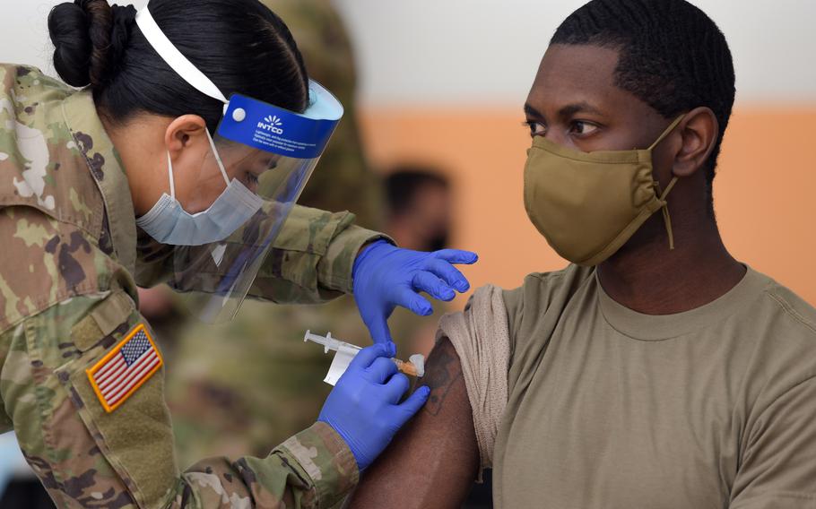 Army Spc. Eyza Carrasco, left, with the 2nd Cavalry Regiment, administers a COVID-19 vaccination at Rose Barracks in Vilseck, Germany, in May 2021. Nearly three-quarters of the U.S. Army community in Europe and Africa are fully vaccinated and 77% of 16- and 17-year-old military children overseas have been inoculated against the coronavirus, health officials say.