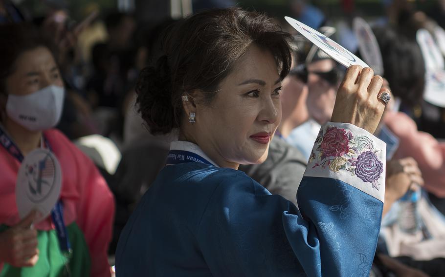 A woman dressed in traditional Korean garb uses a fan to block the sun on her face during a ceremony to dedicate the Wall of Remembrance addition to the Korean War Memorial on the National Mall in Washington, D.C. on Wednesday, July 27, 2022.