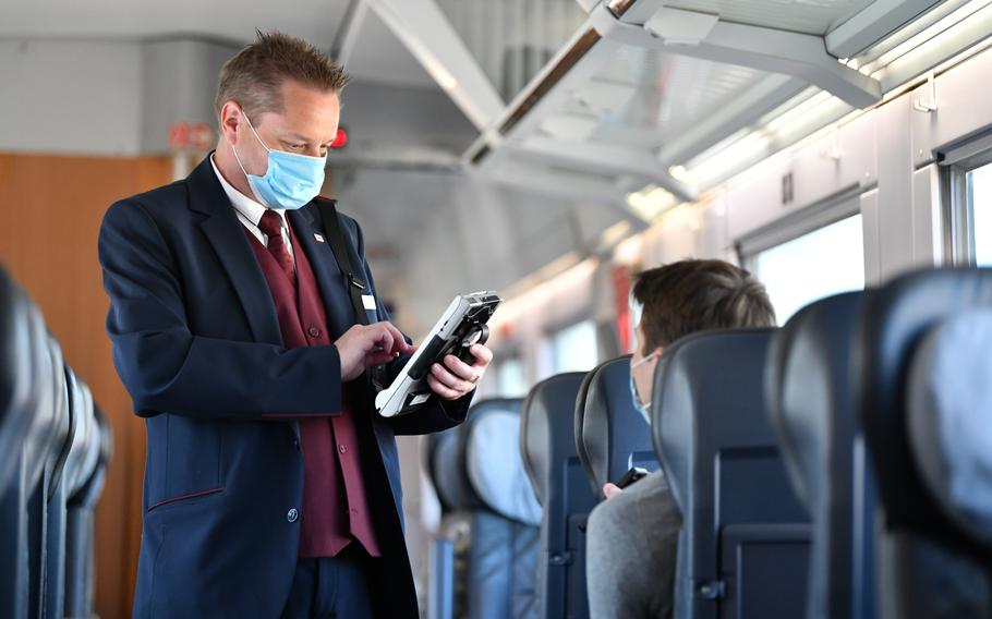 An attendant checks tickets in a German train, June 2, 2020. German transportation ministers this week agreed to a new 49-euro flat-rate ticket for regional buses and trains. 