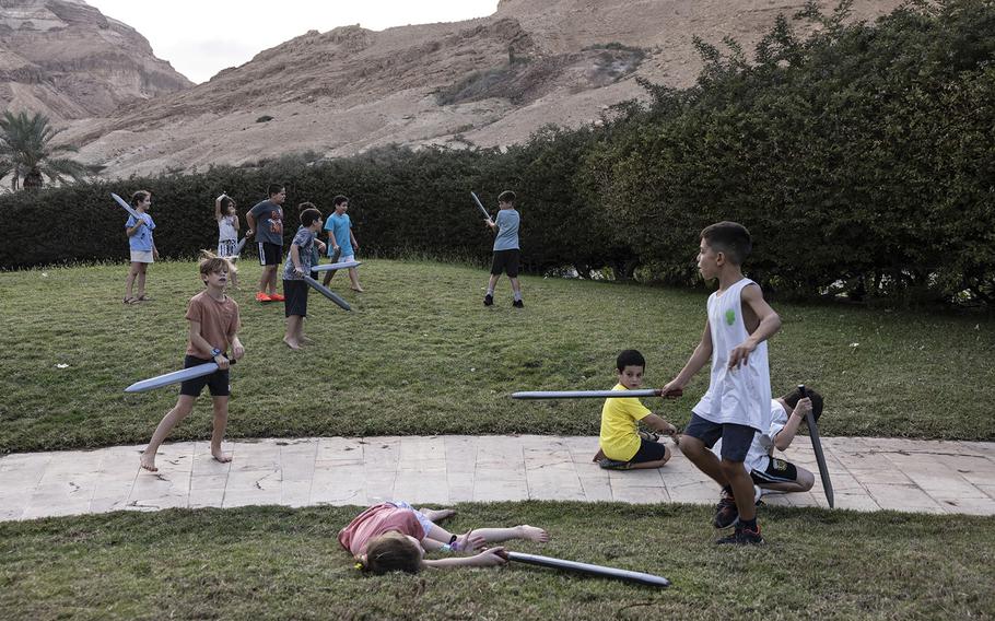 Children of Kibbutz Beeri play with plastic swords on the hotel grounds. 