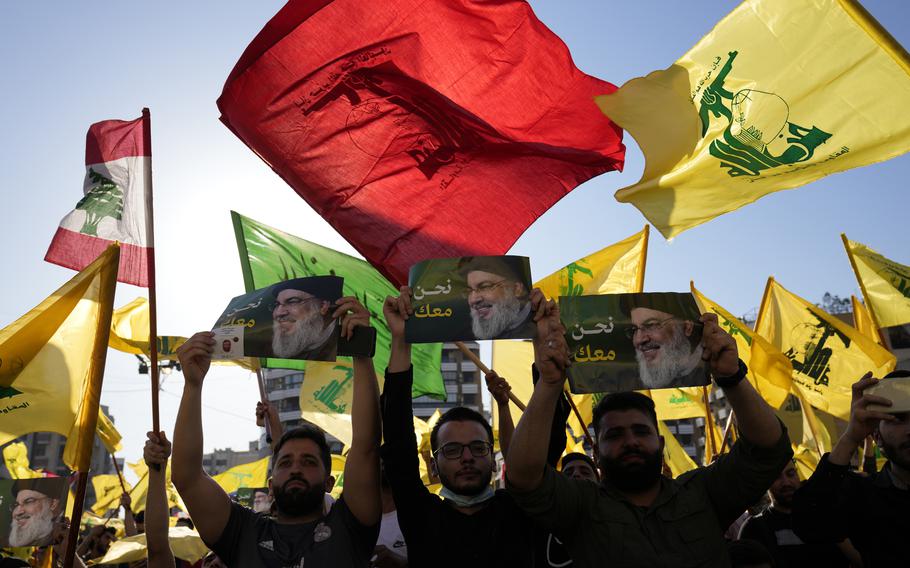 Hezbollah supporters hold up portraits of Hezbollah leader Sayyed Hassan Nasrallah with Arabic words that read: “We are with you,” as others wave their group flags during an election campaign, in the southern suburb of Beirut, Lebanon, on May 10, 2022.