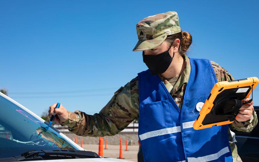 Army Sgt. Maggie Van Wagenen, a combat medic, writes a person's vaccination time on a car windshield June 4, 2021, at the Community Vaccination Center at the Colorado State Fairgrounds in Pueblo, Colo. The soldiers are a part of the federally supported vaccination mission that provides continued, flexible Department of Defense support to FEMA as part of the response to the coronavirus pandemic.