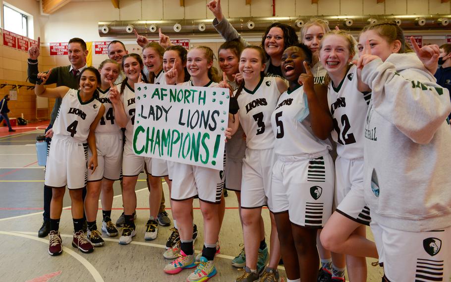 The AFNORTH Lions smile for a group photo on the court after winning against the Ansbach Cougars during the DODEA-Europe Division III girls basketball championship title in Kaiserslautern, Germany, on Saturday, Feb. 26, 2022.