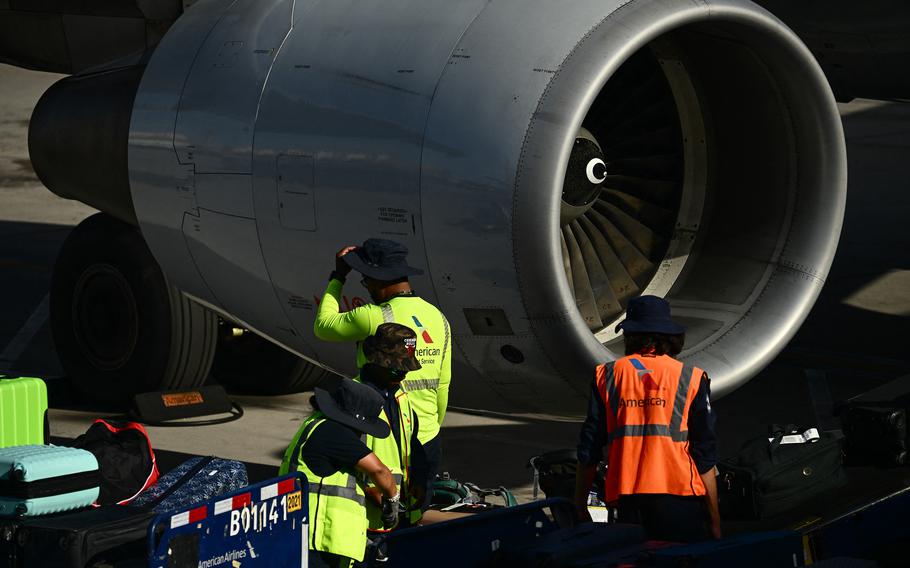 American Airlines ramp workers wear hats to protect themselves from the sun while loading bags onto an aircraft on the tarmac at Phoenix Sky Harbor International Airport during a record heat wave in Phoenix on July 18, 2023. 
