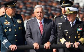 Mexican President Andres Manuel Lopez Obrador, flanked by Defense Secretary Gen. Luis Crescencio Sandoval, left, and Marine Secretary Jose Rafael Ojeda, surveys National Guard troops as the new force is presented at a ceremony, in Mexico City.