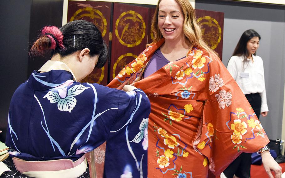 A Japanese service member helps Maj. Michelle Binder wear a yukata during a cultural exchange at the USO on Yokota Air Base, Japan, July 22, 2023. 