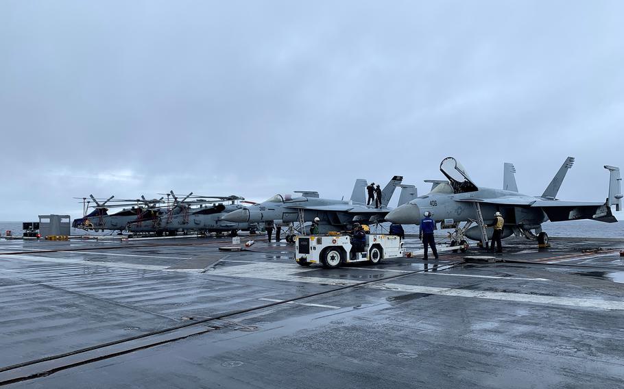 Crews work on aircraft aboard the flight deck of the USS Gerald R. Ford, which is on its first deployment, Sunday, Nov. 13, 2022, in international waters off the Atlantic coast of France.