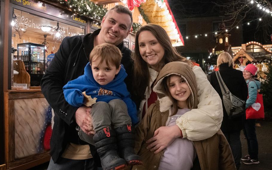 A family of four, including a girl and a young boy, smile in a group photo.