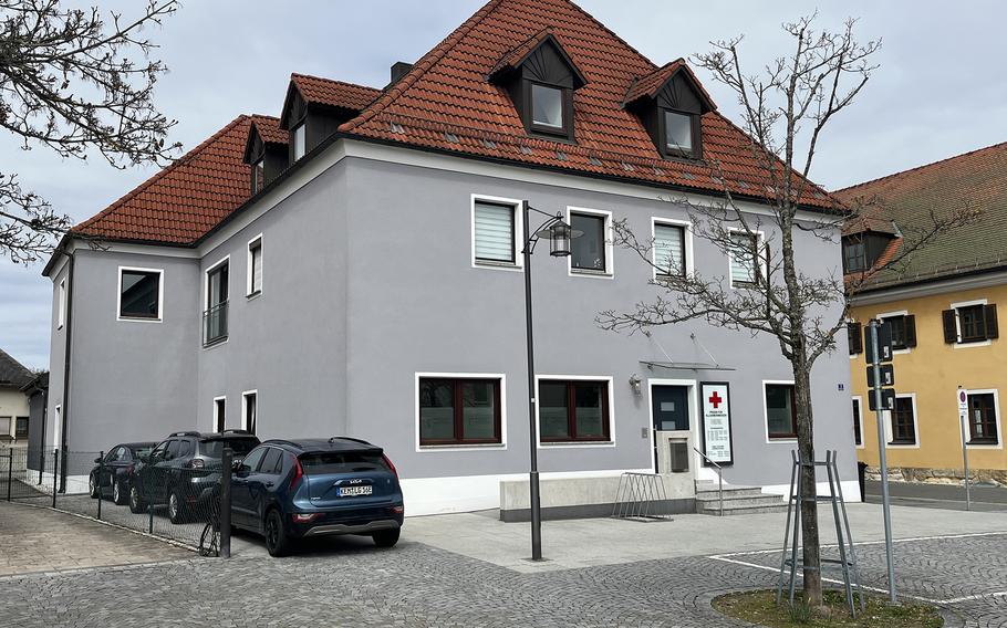 A gray building with white trim and a red roof stands in the spot formerly occupied by a post office. 