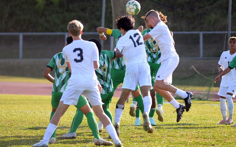 Kadena and Kubasaki players leap to head the ball.