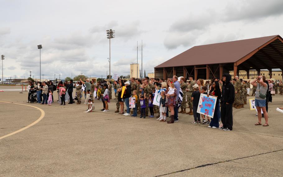 Airmen, friends and family wait in a group while holding up posters
