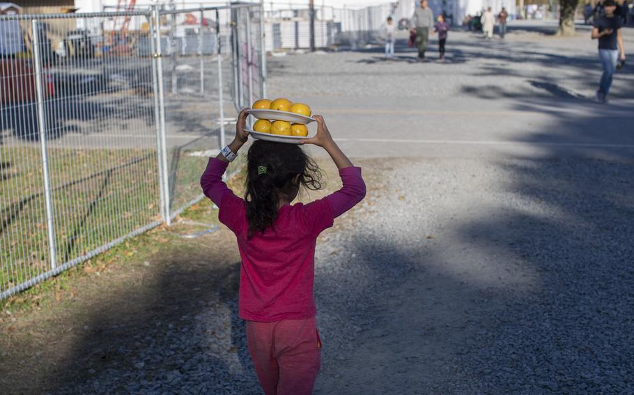 An Afghan girl carries oranges in Liberty Village on Joint Base McGuire-Dix-Lakehurst, N.J., on Nov. 8, 2021. The Defense Department is providing transportation, temporary housing, medical screening, and general support for Afghan evacuees at military bases in the U.S. 