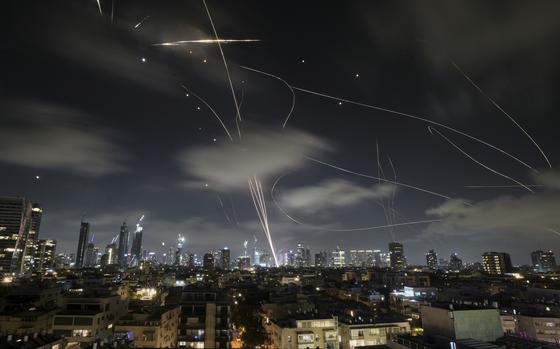 Streaks of light are seen against the nighttime skyline as Israeli Iron Dome air defense system fires to intercept missiles.