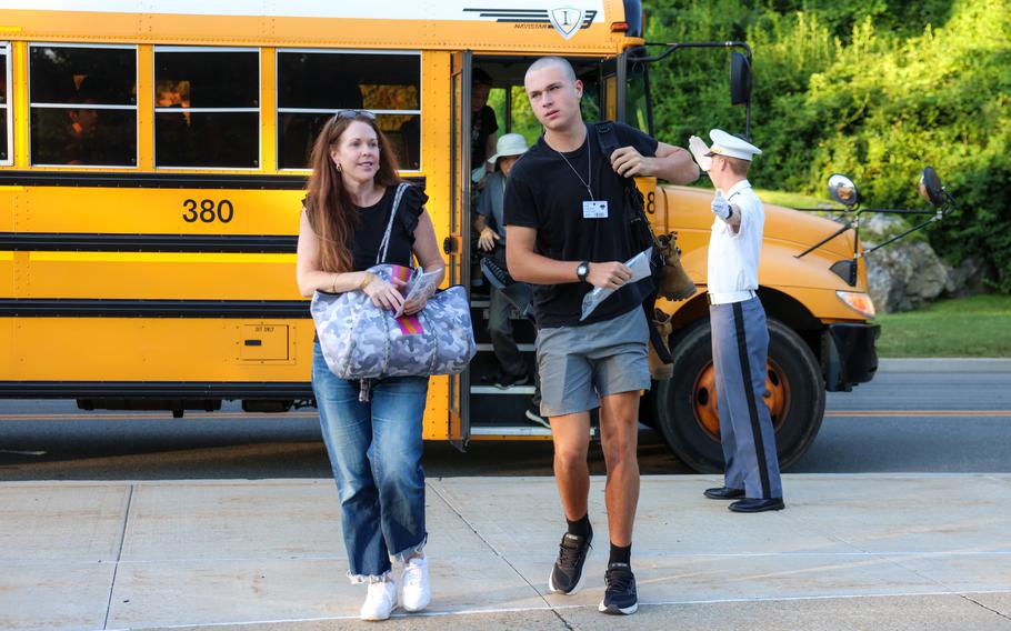 A cadet and his mom get off a bus on campus.