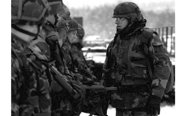 A black and white photo of a man in uniform speaking to other troops.