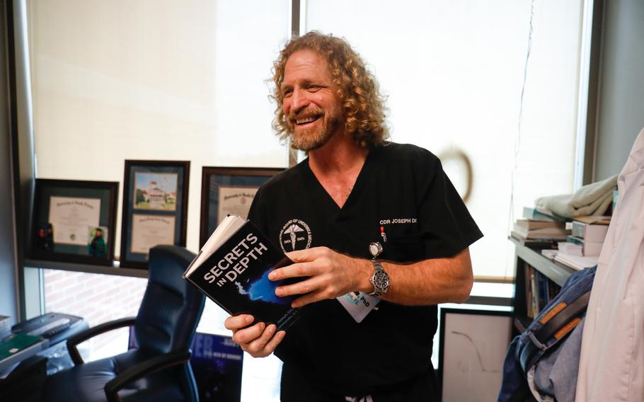 Researcher Joseph Dituri holds a copy of his book inside his office at the Undersea Oxygen Clinic in Tampa, Fla.