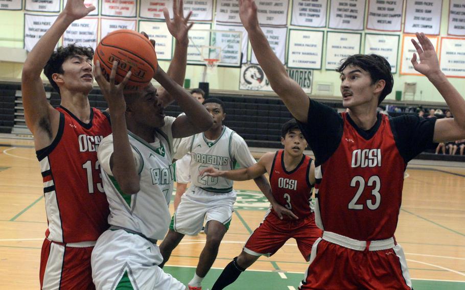 Kubasaki’s Alex James looks to maneuver between two Okinawa Christian defenders during Tuesday’s Okinawa boys basketball game. The Dragons beat the Eagles 66-52.