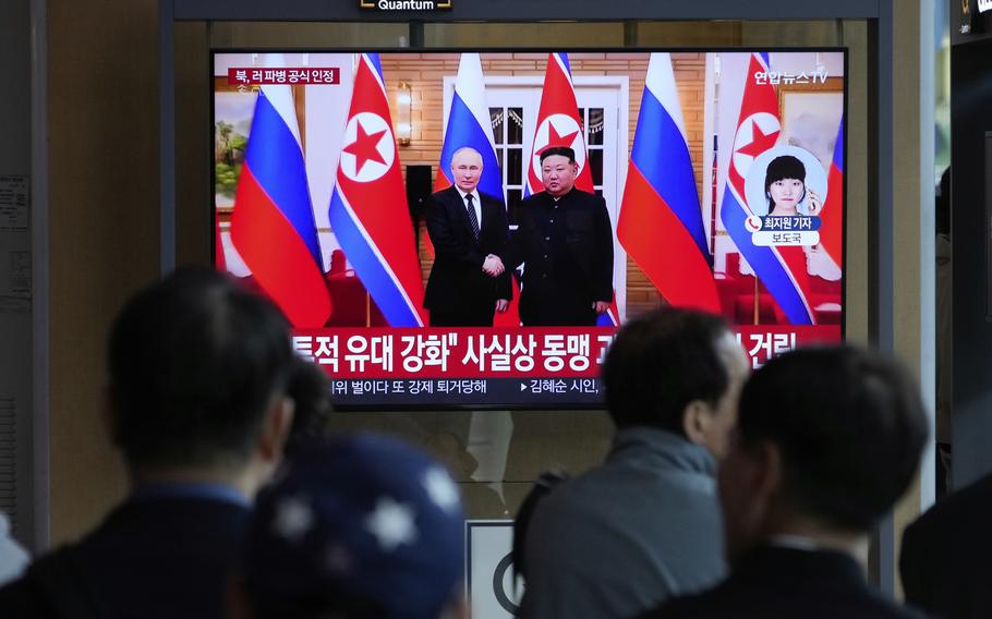 A TV screen shows a file image of North Korean leader Kim Jong Un, right, and Russian President Vladimir Putin in Pyongyang, during a news program.