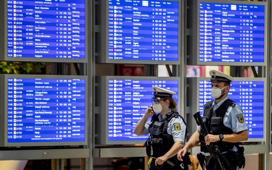 German police officers wearing face mask walk past a flight board in a terminal at the airport in Frankfurt, Germany, Tuesday, May 11, 2021. Several Jewish travelers say the airline Lufthansa blocked more than 100 people from boarding a connecting flight in Frankfurt, Germany, last week.