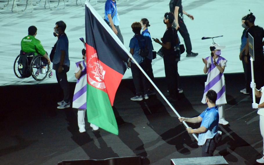 A volunteer carries the flag of Afghanistan, which recently fell to the Taliban, into National Stadium during the Tokyo Paralympics' opening ceremony, Tuesday, Aug. 24, 2021. 