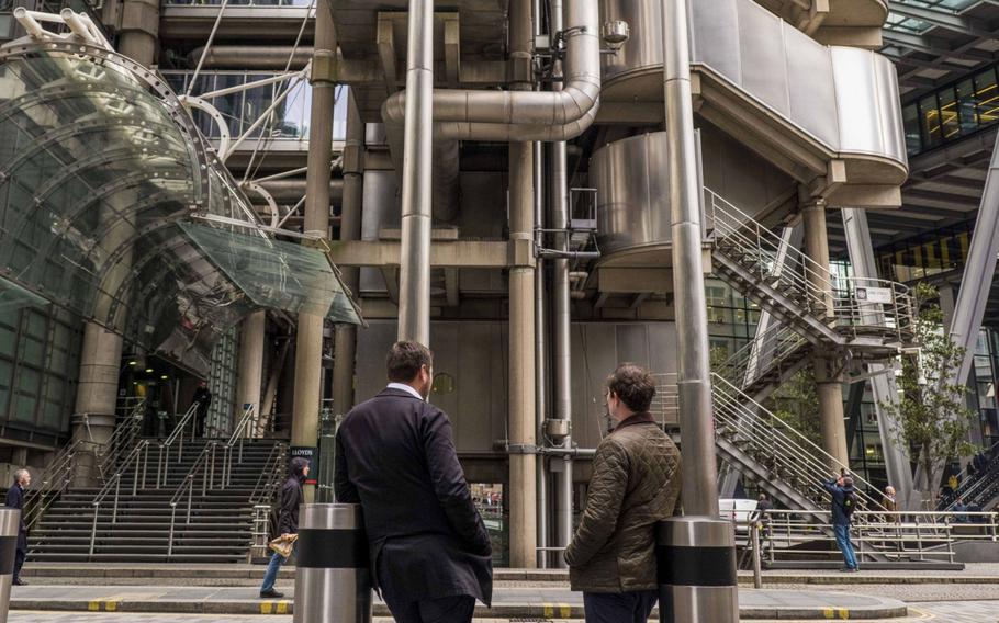 Commuters stand in view of the Lloyds of London building in the City of London on Feb. 17, 2020. 