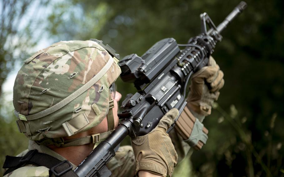 A uniformed troop holds a firearm.