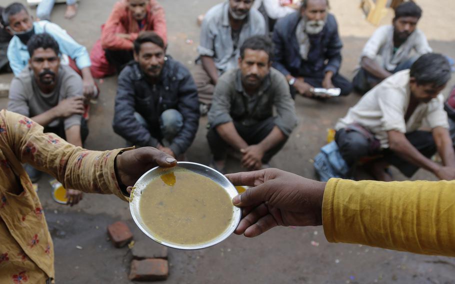 People wait for free food outside an eatery in Ahmedabad, India, on Jan. 20, 2021. Growing numbers of people in Asia lack enough food to eat as food insecurity rises with higher prices and worsening poverty, according to a report by the Food and Agricultural Organization and other UN agencies released Tuesday, Jan. 24, 2023.