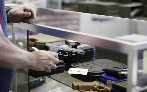 A salesperson takes a Glock handgun out of a case at a store in Orem, Utah, on March 25, 2021. MUST CREDIT: Bloomberg photo by George Frey.