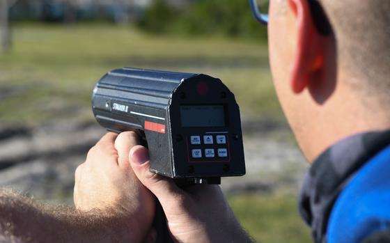 A police officer aims a radar speed gun.