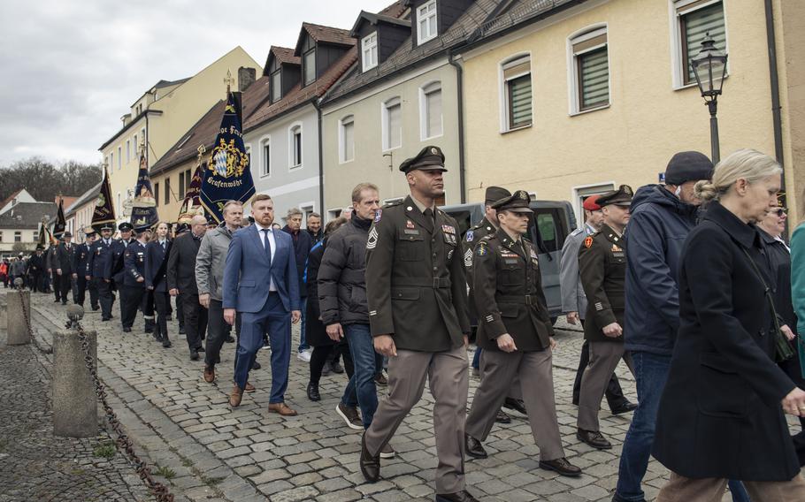 A line of men and women, some wearing service uniforms march