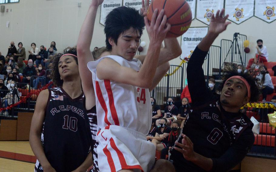 E.J. King's Nolan FitzGerald comes down with a rebound between Matthew C. Perry's Shion Fleming and Denzel Gray during Saturday's DODEA-Japan boys basketball game, which the Samurai won 48-39.