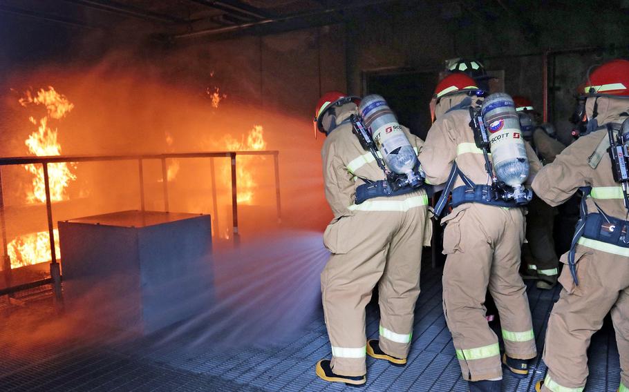 Steam rises as Navy ROTC midshipmen begin to hose down a propane-fueled fire in a simulated ship's engine room at Naval Station Mayport.