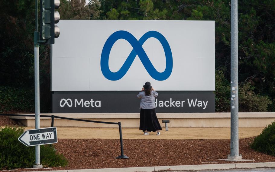 A visitor takes photographs of Meta Platforms signage outside the company’s headquarters in Menlo Park, California on Oct. 29, 2021. 