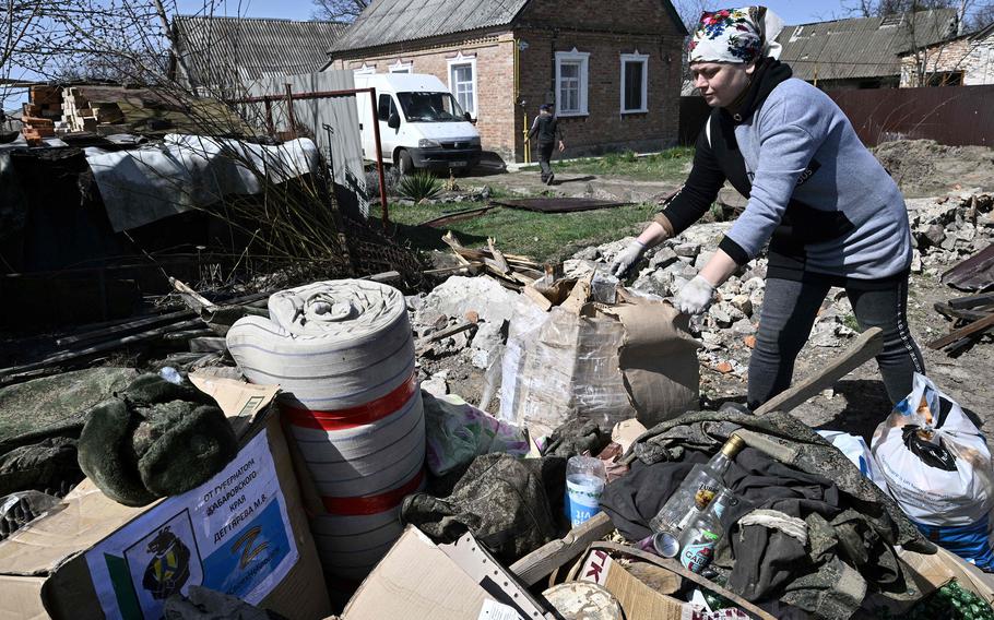 People clean houses of belongings and garbage left by Russian servicemen who stayed there, in the village of Andriivka, Kyiv region, on April 14, 2022. 