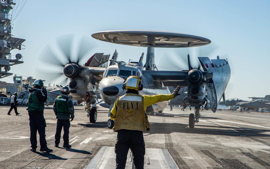 Petty Officer 3rd Class Matthew Tecson, an aviation boatswain’s mate, directs the pilot of an E-2D Hawkeye on the flight deck of the aircraft carrier USS Harry S. Truman in the Adriatic Sea on Feb. 24, 2022. 