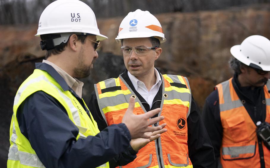 U.S. Secretary of Transportation Pete Buttigieg, center, visits with U.S. Department of Transportation investigators at the site of the train derailment in East Palestine, Ohio, on Thursday, Feb. 23 2023. 