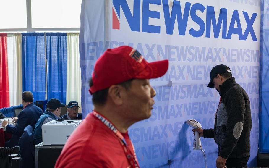 A Newsmax television crew member steam irons a backdrop for the organization during a conservative political conference in National Harbor, Md., on Feb. 24. 