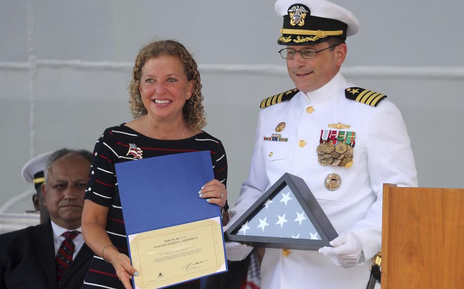 U.S. Rep. Debbie Wasserman Schultz, D-Fla., left, presents a flag that flew over the U.S. capital to Capt. James Quaresimo, the commanding officer of the USS Fort Lauderdale (LPD 28), gives a speech during the commissioning of the ship, on Saturday, July 30, 2022, at Port Everglades in Fort Lauderdale, Florida. 