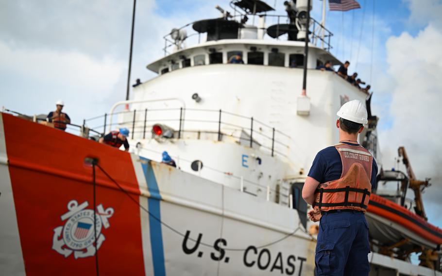 A Coast Guard member stands on the pier as the cutter sails in.