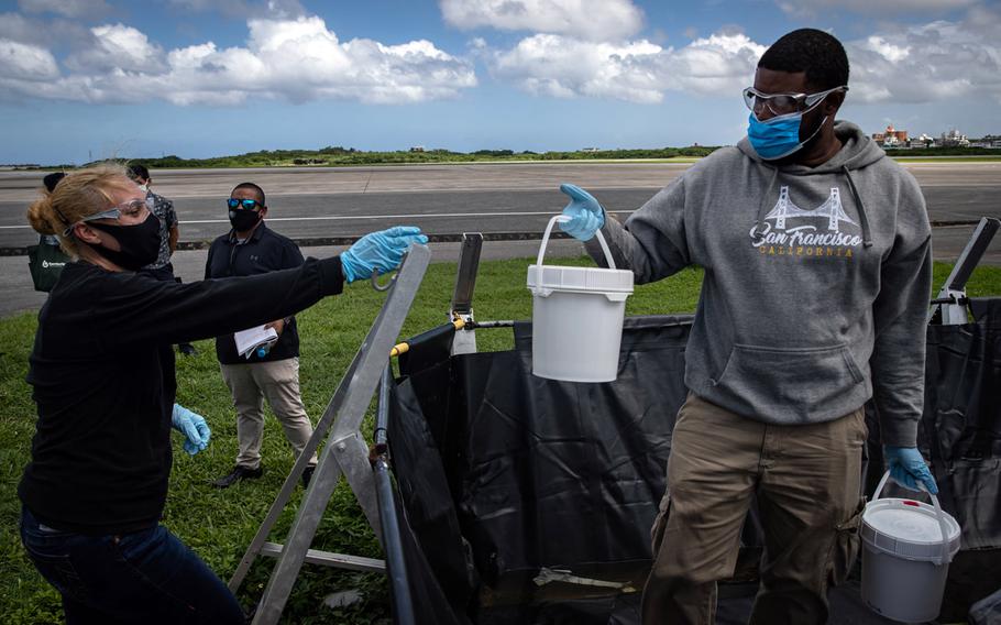 Japanese and U.S. military officials collect samples of treated wastewater at Marine Corps Air Station Futenma, Okinawa, July 19, 2021.